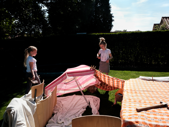 Sfeerbeeld waarin twee kinderen op een zonnige dag een hut bouwen in de tuin