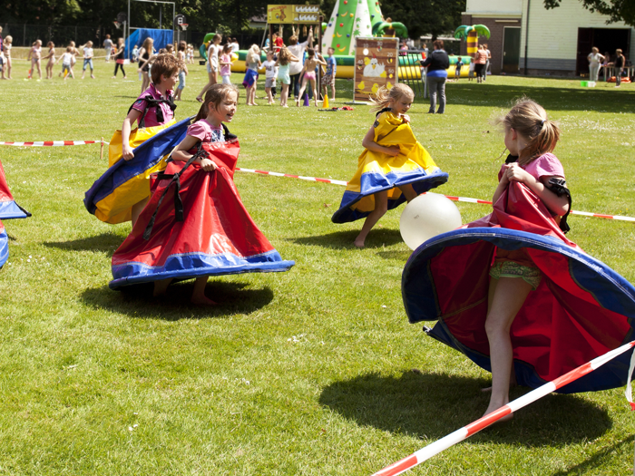 Afbeelding van een aantal kinderen die, uitgedost in grote rokken, een speciaal soort balspel spelen