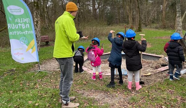 Kinderen met bouwhelmen graven in de speelplek van Bospark Vollenhove.