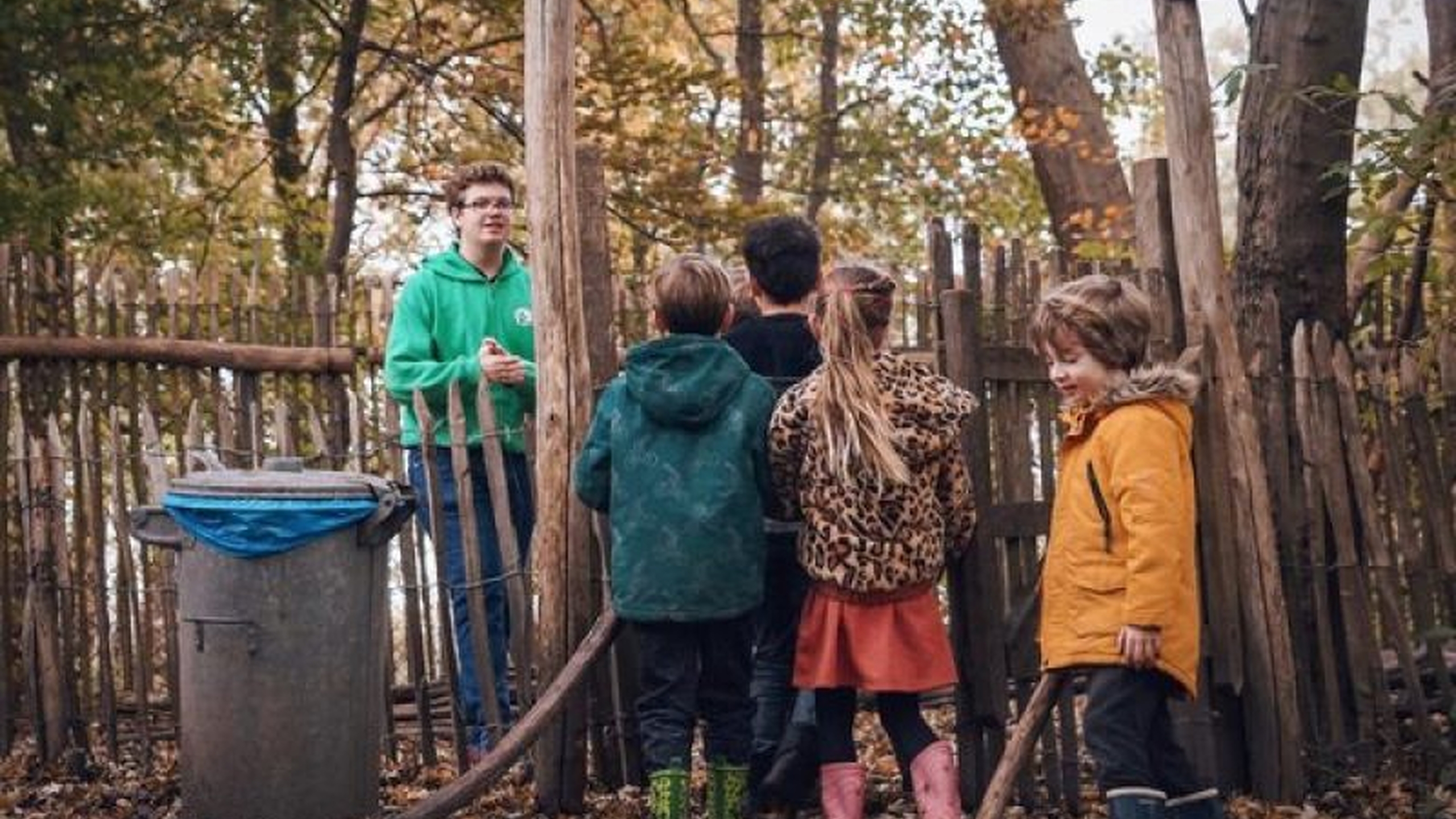 Kinderen staan voor een hek in een speeltuin. Jantje Beton