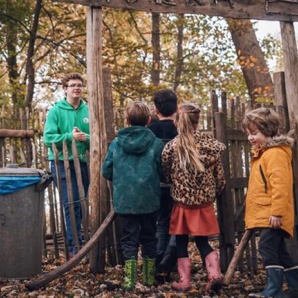 Kinderen staan voor een hek in een speeltuin. Jantje Beton