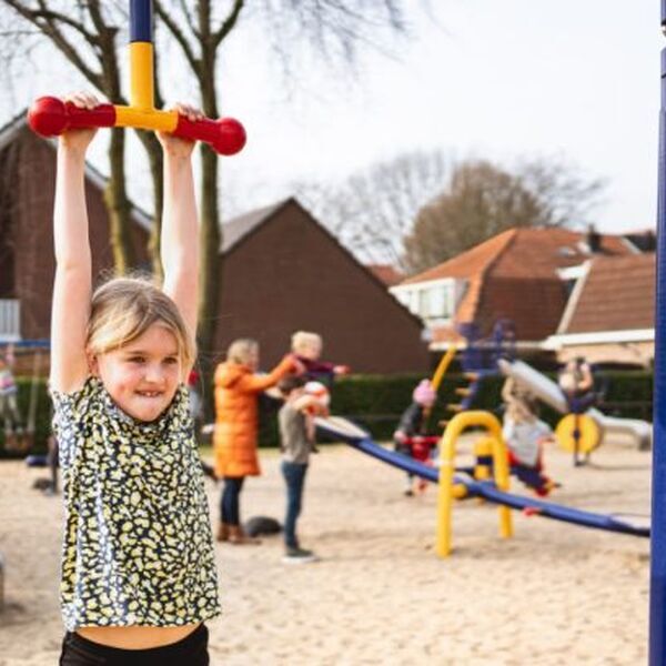 Kind hangt aan speelrek in een speeltuin. Beheerde speeltuinen leveren de maatschappij geld op door onder ander minder zorgkosten - Jantje Beton