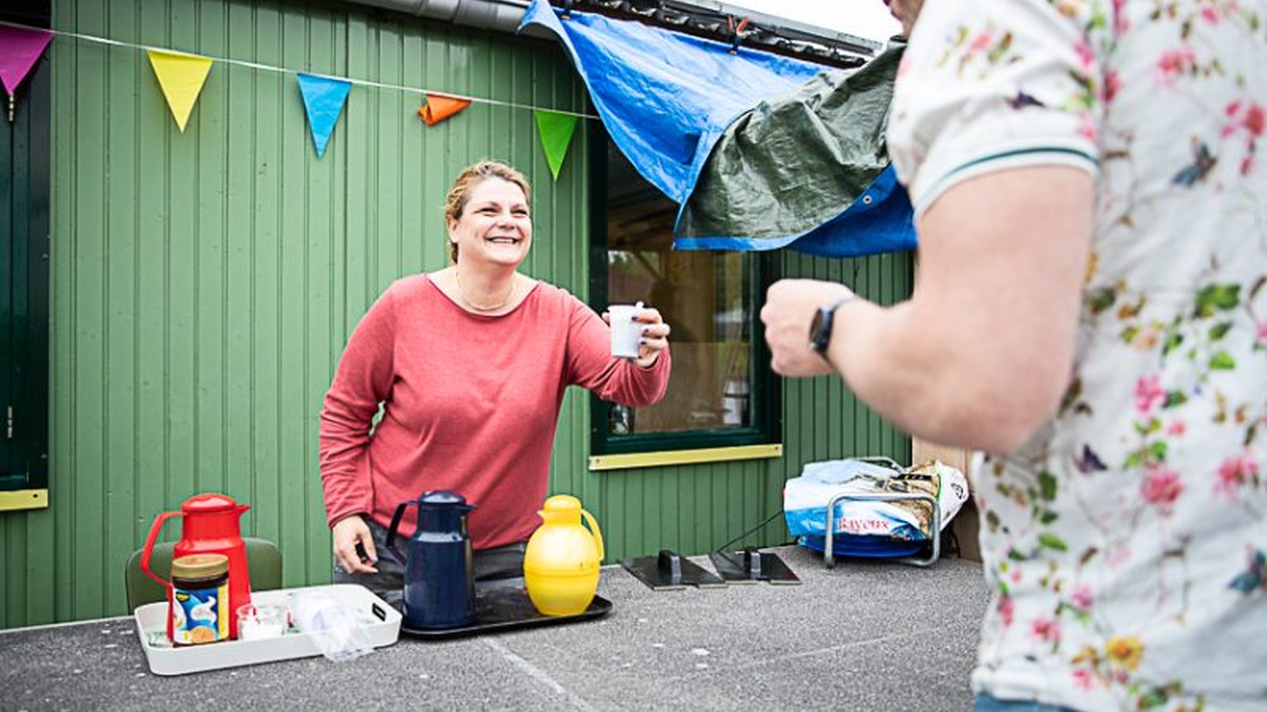 Een vrouw in een speeltuin doet een geldinzamelingsactie door verkoop van koffie - Jantje Beton