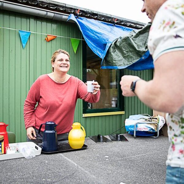 Een vrouw in een speeltuin doet een geldinzamelingsactie door verkoop van koffie - Jantje Beton