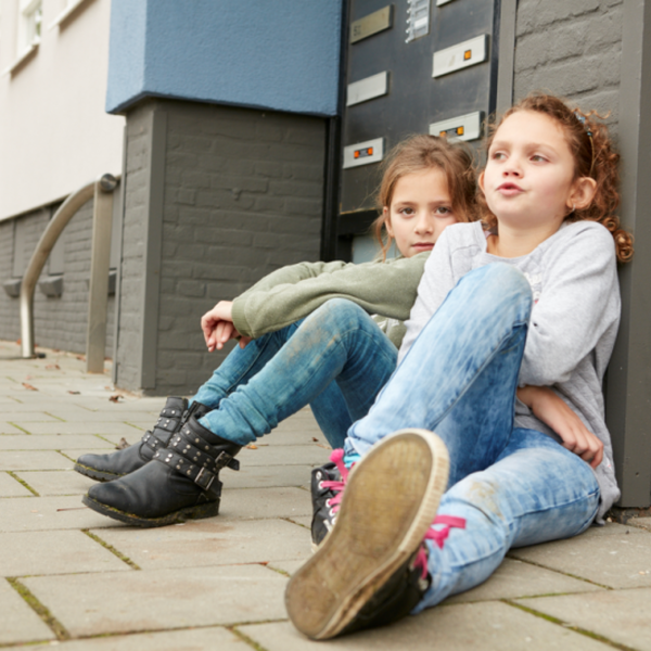 Kinderen zitten op de stoep. Wij raden het speeltuinen aan te werken met een meldcode huiselijk geweld en kindermishandeling - Jantje Beton