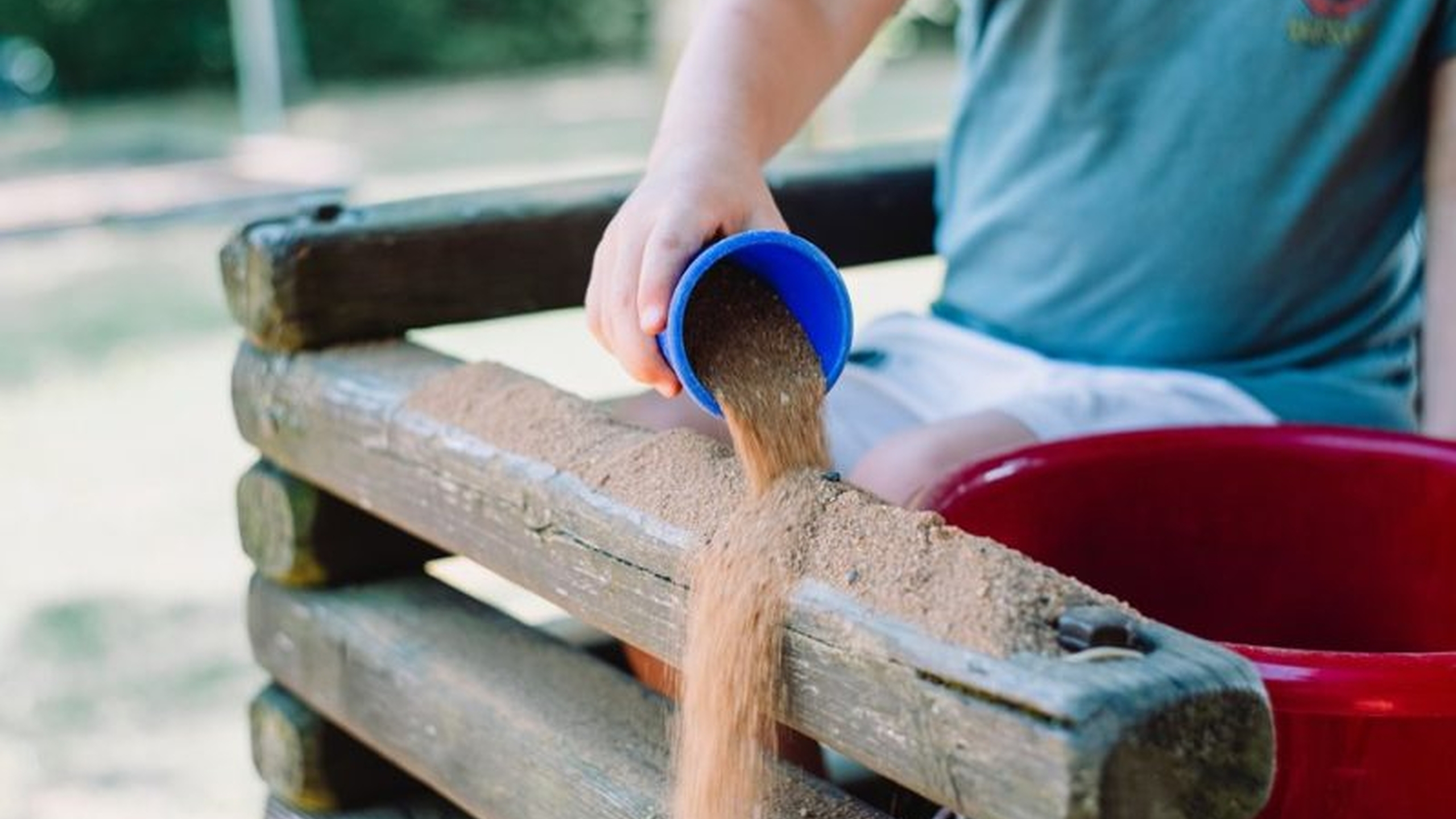 Kind gooit zand over een speeltoestel. Als speeltuin of kindervakantieorganisatie kan je via automatische incasso betalen aan Jantje Beton om tijd te besparen.