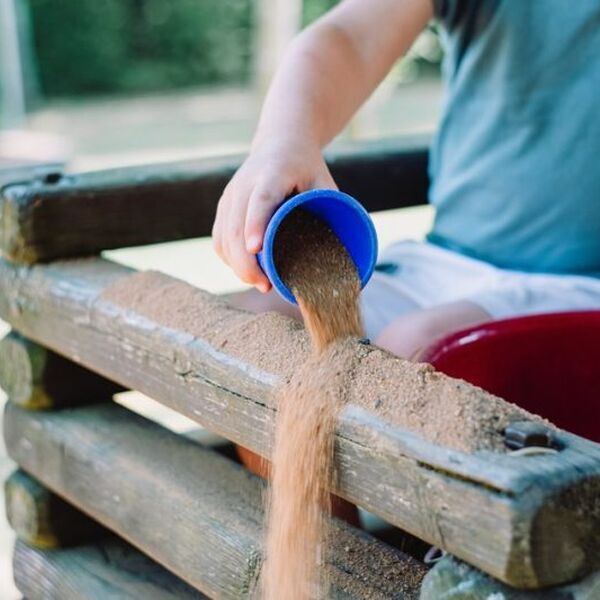 Kind gooit zand over een speeltoestel. Als speeltuin of kindervakantieorganisatie kan je via automatische incasso betalen aan Jantje Beton om tijd te besparen.