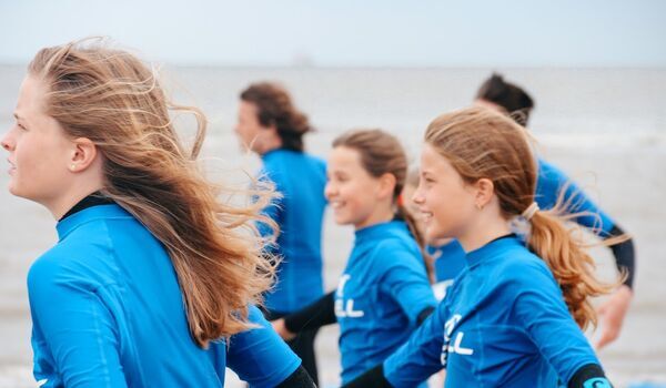 Kinderen lopen over het strand in de wind. Je kan als aangesloten organisatie - Speelpartner - in aanmerking komen voor teruggave van de energiebelasting - Jantje Beton